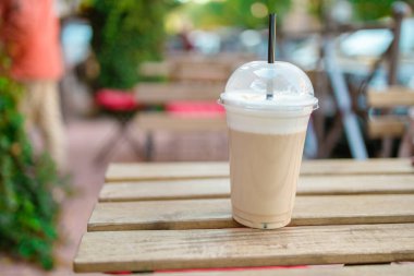 Dışarıdaki kafenin ahşap masasında plastik bir fincan sıcak kahve.