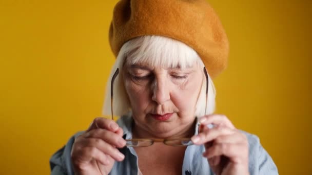 Happy 50s 40s Frau erstaunt Gesicht Touch Brille Blick Kamera isoliert über gelben Farbhintergrund — Stockvideo