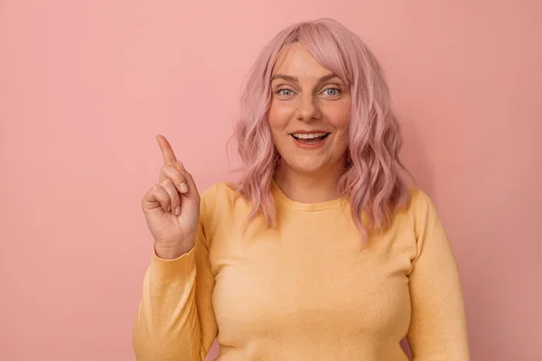 注意プロモーションバナー ピンクの髪をした魅力的な若い白人女性は ピンクの背景に隔離されたコピースペースの側に指を指しています モックアップコピースペース — ストック写真
