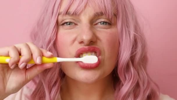 Gelukkig glimlachende vrouw poetsen gezonde tanden met tandenborstel, zorgt voor mondhygiëne op roze achtergrond. Tandheelkundige verzorging — Stockvideo