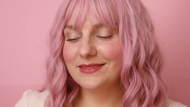 Closeup portrait of pretty young female with bottle of perfume and applying it. Beautiful girl using perfume over bright pink color background — Stock Video