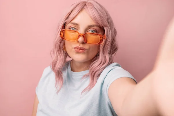有魅力的三十来岁女性博主 戴着明亮的橙色时髦眼镜 看着相机 带着粉红背景的自拍 人的概念 — 图库照片