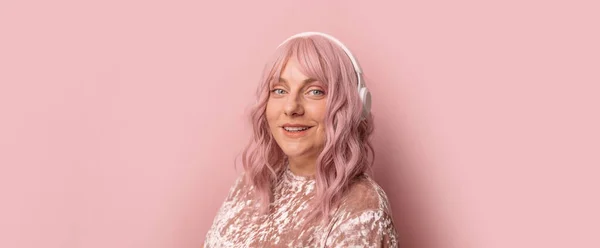 Lächelnd fröhlich lustig schöne attraktive junge Frau, die Musik über Kopfhörer hört und Spaß auf rosa Hintergrund hat. Banner mit Copyspace. — Stockfoto