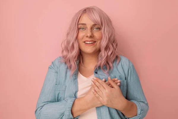 Mulher elegante atraente bonita segurar as mãos com as mãos no peito isolado em um fundo rosa, conceito de ajuda voluntário de saúde. — Fotografia de Stock