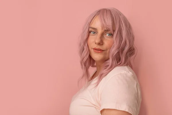 Cabelo rosa jovem menina bonita olha na câmera no fundo pastel rosa — Fotografia de Stock