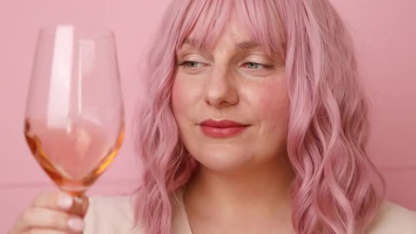 Mulher bonita bebendo um copo de vinho rosa isolado sobre fundo rosa — Vídeo de Stock