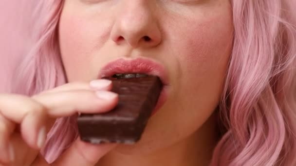 Belle jeune fille manger des biscuits au chocolat isolé sur fond rose — Video