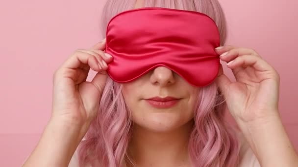 Κουρασμένη νυσταγμένη γυναίκα φοράει eyemask, θέλει να κοιμηθεί, δυσαρεστημένη να ξυπνήσει πολύ νωρίς, ποζάρει σε ροζ φόντο τοίχου — Αρχείο Βίντεο