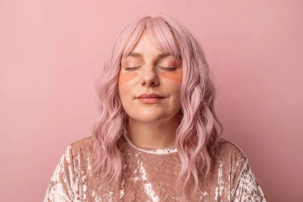 ピンクの背景にピンクの目のパッチの下にピンクを適用し、閉じた目を持つ幸せな白人女性の肖像画。化粧品 — ストック写真