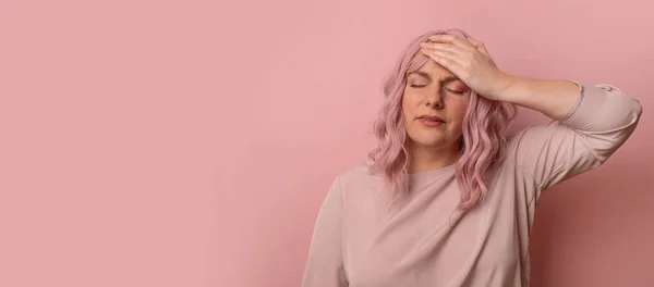 Schöne Frau in den 30er Jahren, die mit der Hand auf dem Kopf vor Kopfschmerzen steht, weil der Stress über dem isolierten rosafarbenen Hintergrund liegt. Migräne. Hand in Hand. — Stockfoto