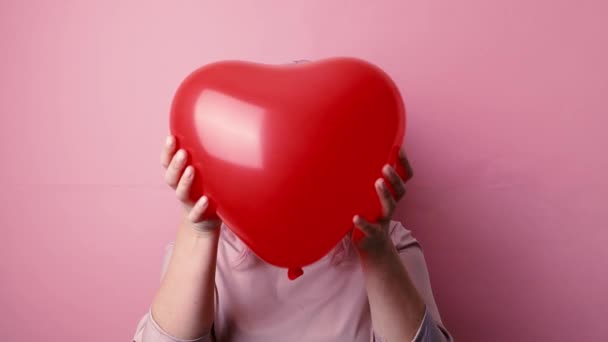 Festa di San Valentino. Giovane bella caucasica glamour donna sorridente tenendo palloncino rosso a forma di cuore isolato su sfondo rosa. — Video Stock