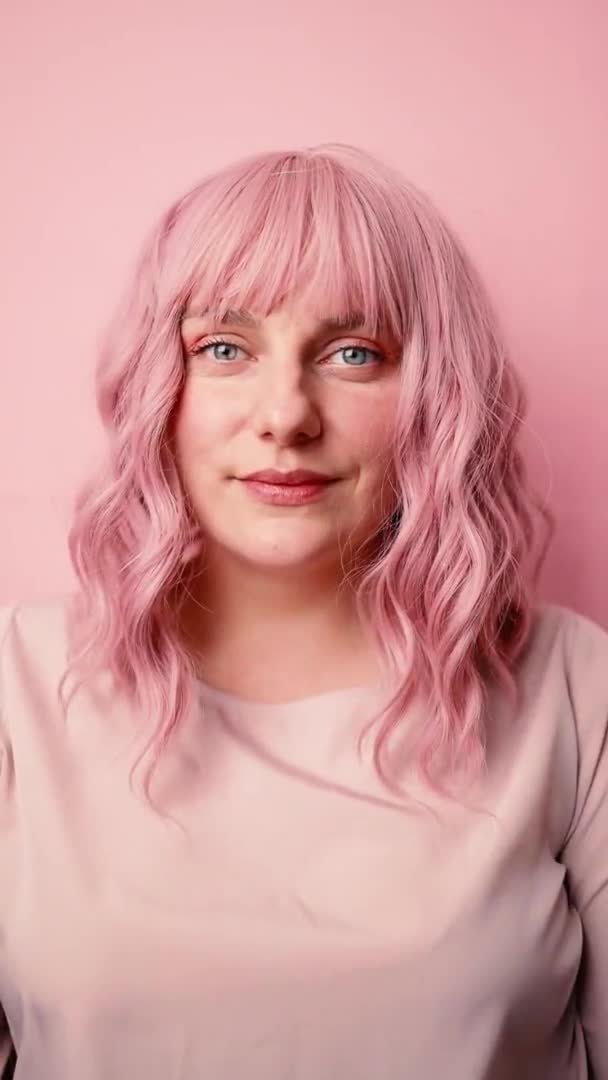 Портрет красивої молодої жінки, яка дивиться на камеру і посміхається, роблячи селфі фото ізольованого рожевого фону, концепція способу життя людей. Вертикальне відео — стокове відео