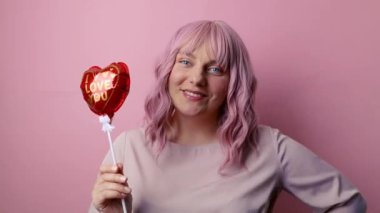 Balon şeklinde kalpler tutan mutlu pozitif kadın pembe arka planda izole edilmiş eğleniyor. Kadınlar, Anneler, Sevgililer Günü, Doğum günü Kutlaması