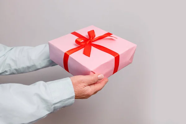 Närbild skott av kvinnliga händer håller överraskning presentförpackning på rosa pastell bakgrund med kopieringsutrymme. Alla hjärtans gåva — Stockfoto