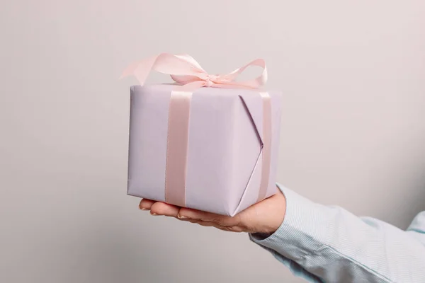 Närbild skott av kvinna händer håller presentförpackning på rosa pastell bakgrund med kopia utrymme. — Stockfoto