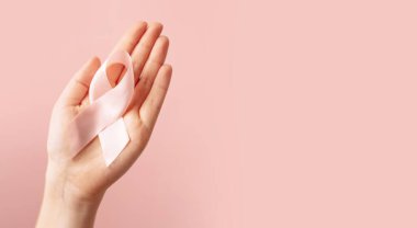 Avuç içi kanserinin sembolü olan pembe kurdeleli kadın, izole edilmiş pastel arka planda fotokopi alanı ile birlikte pembe renkte bilinç sahibi.