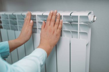 Kış mevsiminde evde kadın elinin kesilmiş fotoğrafı pil sıcaklığını ölçer.