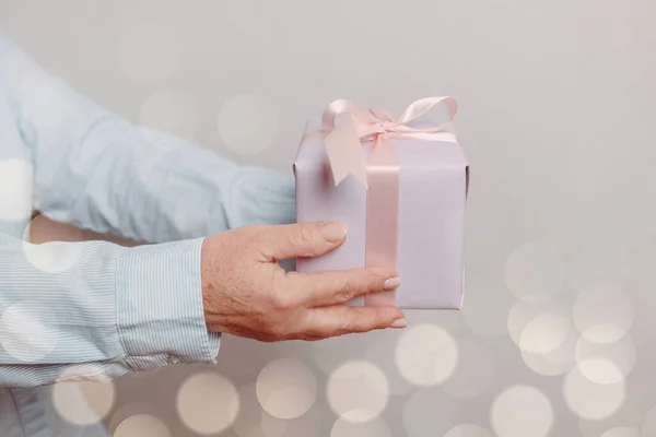 Närbild skott av kvinna händer håller presentförpackning på rosa pastell bakgrund med kopia utrymme. — Stockfoto