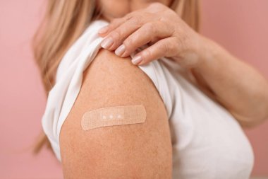 COVID-19 aşısından sonra 50 'li yaşlarda bir kadın omuz gösteriyor. Aşı, sürü bağışıklığı, yan etki, artırıcı doz