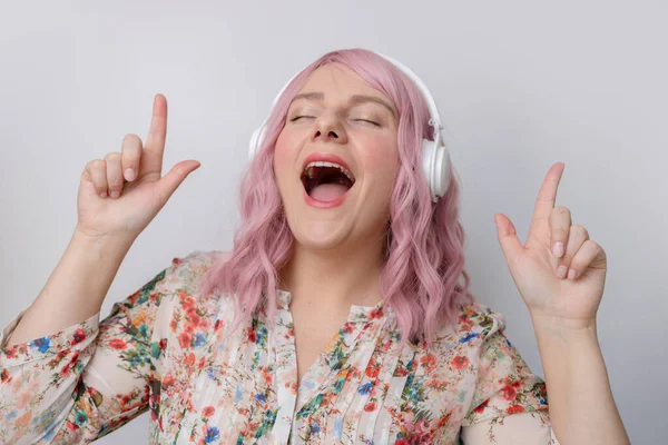 Jovem mulher usa fones de ouvido ouvir música cantar música isolada no estúdio de fundo pastel. Tecnologia e comunicação de pessoas — Fotografia de Stock