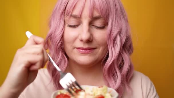 Glücklich hungrig positiv gesunden Lebensstil Mädchen essen gesunden Salat isoliert über gelbem Hintergrund — Stockvideo