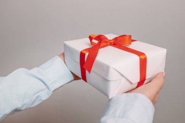 Gri bir arkaplan üzerinde kadın elleri hediye. Banner, boşluğu kopyala.