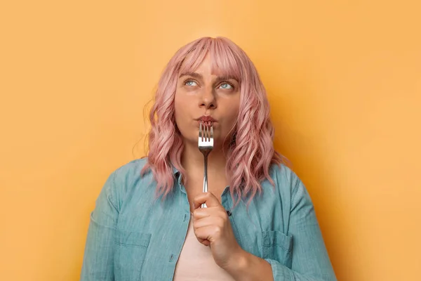 Retrato de mujer hambrienta sosteniendo tenedor aislado sobre fondo amarillo de la pared. Concepto de salud —  Fotos de Stock