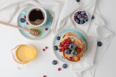 Taze yaban mersinli, ahududu ve bal şuruplu leziz krepler açık arkaplanlı gri bir masada, kopyalama alanı. Üst manzara, düz uzanma