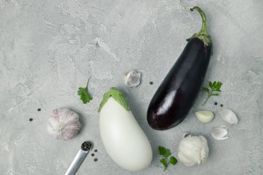 Beyaz ve mavi taze çiğ patlıcan sebze ve sarımsak. Gri arka planda, üst tarafta. Sağlıklı vejetaryen diyeti