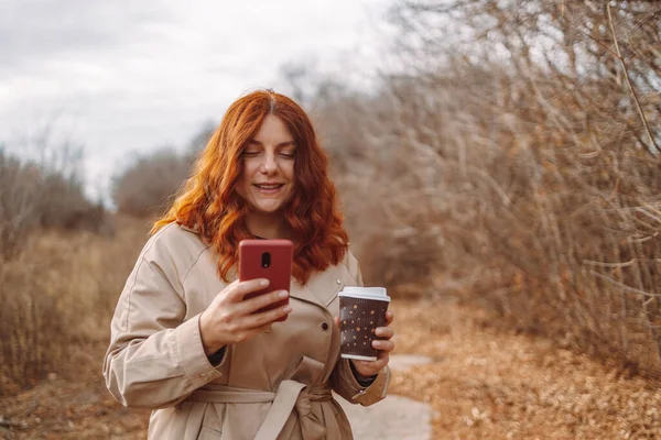 Akıllı telefon kullanan ve kahve servisi yapan güzel genç bir kadın.