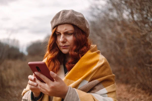 Hüsrana uğramış kız, sonbaharda parkta yürürken cep telefonuyla ilgili sorunlar yaşıyor.