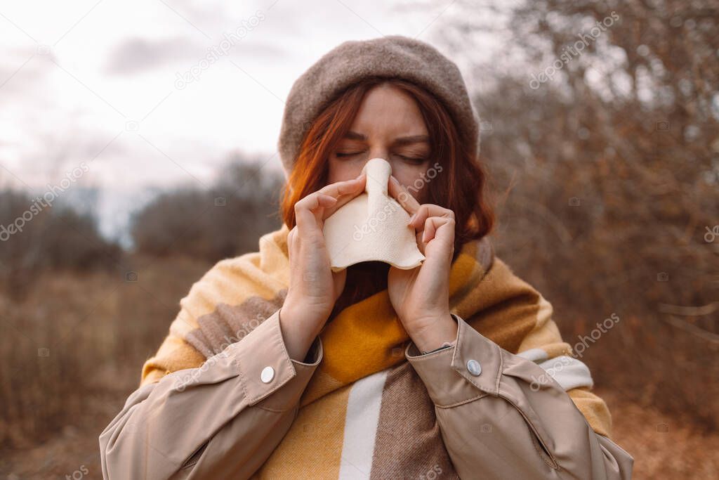 Ill caucasian female with handkerchief runny nose cold infection in a cold autumn day.