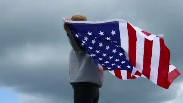 Victoire. Heureuse jeune femme patriotique a levé un drapeau américain dans ses mains. Fille voyageant profiter de la vue randonnée aventure vacances plein air mode de vie actif — Video