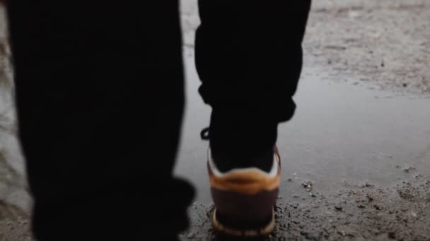Női lábak sportcipőben, tócsákon sétálva, miközben esik az őszi parkban. — Stock videók