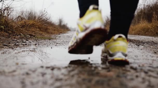 秋天，穿运动鞋的女人穿着运动鞋跑着，跳着水花飞溅的水坑，跌落在地上 — 图库视频影像