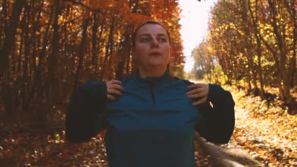 Atleta corredor esticando braços se preparando para correr treino ao longo ao ar livre no outono parque florestal na natureza. Conceito de treino, bem-estar e menina esporte — Vídeo de Stock