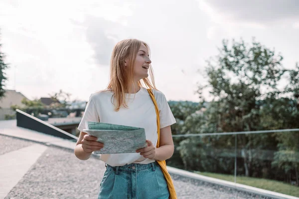 Genç sarışın kadın turist haritası ile şehir şehrini geziyor. — Stok fotoğraf