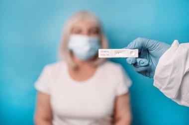 Doktor elinde negatif hızlı yanal akış COVID 19 testi açık mavi arkaplan üzerinde