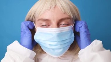 Genç bayan doktor ya da koruyucu giysili hemşire. Tıbbi maske eldivenli. Laboratuvarda Corona virüsünün önlenmesi için yüzüne maske takıyor..
