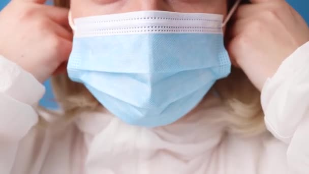 Близько 30 років жінка-лікар знімає захисну маску для обличчя і дивиться на камеру під час пандемії ковадла-19 під час роботи в клініці — стокове відео