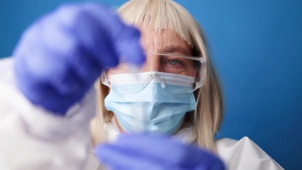 Close up of a doctor in medical PPE suit holds COVID-19 coronavirus PCR test — Stock Video