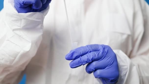 Arzt im Schutzanzug medizinische Maske Handschuhe mit Speichelprobe für diagnostische Covid 19 Coronavirus-Virus auf blauem Hintergrund — Stockvideo