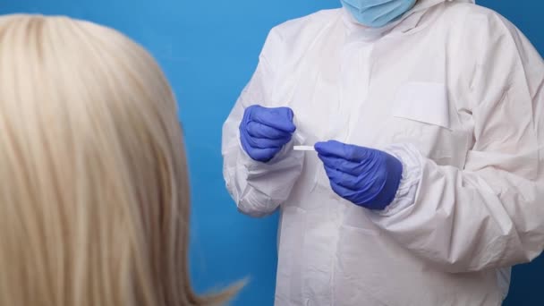 Médecin faisant un test PCR nasal pour les femmes des années 50, en utilisant un bâton d'écouvillon stérile. Analyse du coronavirus, vérification de la santé sur fond bleu — Video