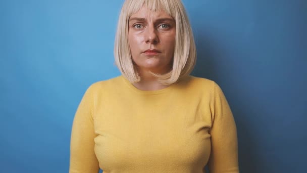 Frightened angry caucasian woman in yellow sweater crossing hands makes stop gesture, demonstrates rejection isolated over blue background. — Stock Video