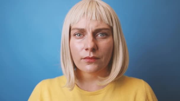 Fechar-se de uma jovem triste caucasiana de 30 anos mulher vestindo camisola amarela cruzando as mãos faz parar gesto olhar câmera isolada no estúdio de fundo de cor azul. — Vídeo de Stock