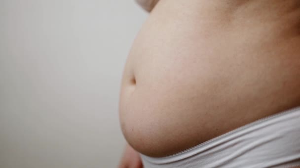 Fat female belly, woman holding skin to check cellulite. Flabby skin on a fat belly, plastic surgery concept on gray background — Stock Video