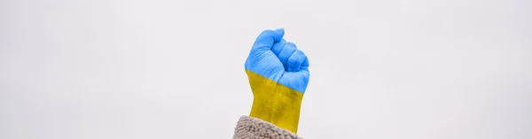 Female hand fist painted in Ukraine flag colors yellow-blue against sky. Stop war between Russia and Ukraine. International political relationship between Ukraine and Russia. — Stock Photo, Image