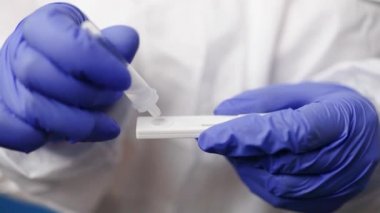 Tıbbi plazma giysisi giymiş bir doktor kovid antijen testi yapıyor. Antijen Coronavirus hastalığının varlığını tespit etmek için laboratuvar antikor testleri yapıyor..