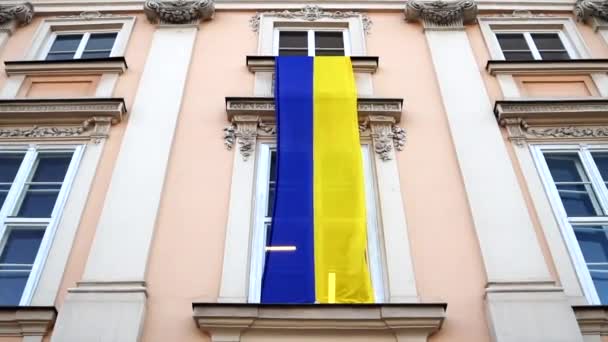 Duża ukraińska flaga na ścianie budynku przy ulicy miejskiej. Wojna na Ukrainie — Wideo stockowe
