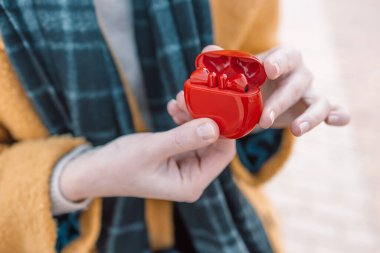 Kadın eli, şehir caddesindeki kırmızı çantadan kablosuz kulaklıkları çıkarır.